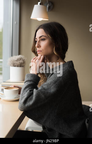 Close up di pensosa donna con la mano sul mento un caffè al caffè Foto Stock