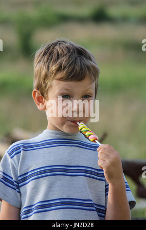 Bel ragazzo mangia caramelle colorate Foto Stock