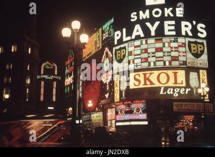 Piccadilly Circus a Londra, Inghilterra 1957. Il luminoso di notte le luci di Piccadilly Circus a Londra in Inghilterra nel 1957. Dominato da una sigaretta giocatori annuncio pubblicitario e datata dalla inserzione per l'insonnia è buono per voi film, comparsa precoce di Peter Sellars prima divenne famoso (vedere in basso a destra della foto). Fotografia di Tony Henshaw Foto Stock