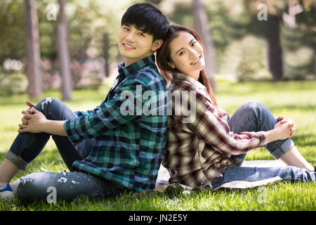 Coppia giovane seduto sull'erba Foto Stock