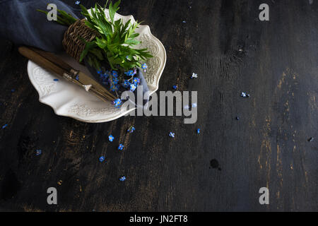 Estate tavola floreale impostazione con blu brillante dimenticare-me-non fiori sul tavolo di legno Foto Stock