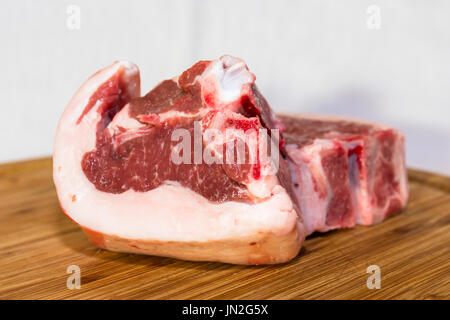 Un display di due prime crudo tagliato costolette di agnello su un tagliere di legno. Perfetto per la cottura alla griglia o arrosto per un pasto delizioso. Foto Stock