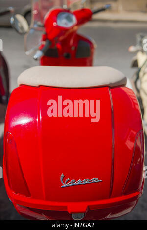 Red scooter Vespa, un rosso scooter parcheggiato in una strada a Siracusa, in Sicilia. Foto Stock