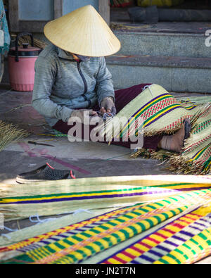 Donna vietnamita nel cappello conico tessitura tradizionale tappeto reed Foto Stock