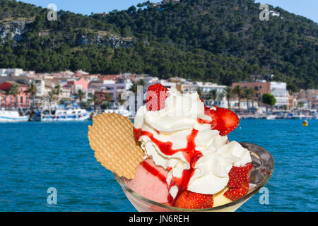 Gelato alla fragola con fragole fresche e crema in sottofondo un bellissimo Mar Mediterraneo bay. Foto Stock