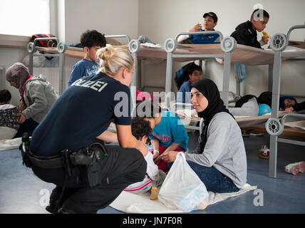 Passau, Germania - 2 Agosto 2015: Una poliziotta tedesco sta prendendo cura di un giovane rifugiato madre e bambini all'area di registrazione in Passau, Bavar Foto Stock