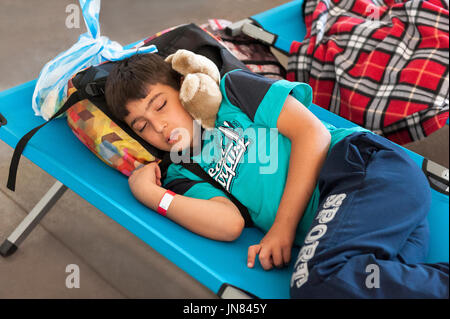 Passau, Germania - 1 agosto 2015: rifugiato siriano ragazzo dormiva in un accampamento di registrazione in Passau, Germania. Egli è stanco dopo un lungo viaggio in Europa. Foto Stock