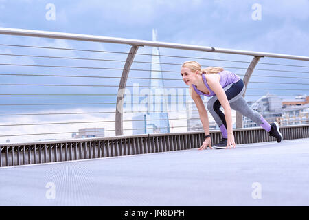 Una giovane donna si prepara a sprint sul Millennium Footbridge Foto Stock