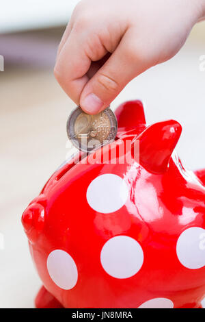 Bambino gettato in Piggy coin - due euro Foto Stock