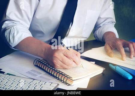 Imprenditore iscritto dati finanziari in libro contabile. Foto Stock