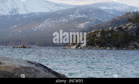 Vista sulle montagne con la neve attraverso il lago Foto Stock