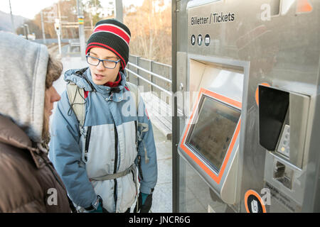 Ragazzo e ragazza di acquistare i biglietti presso la biglietteria presso la fermata del tram di Bergen, Norvegia Foto Stock