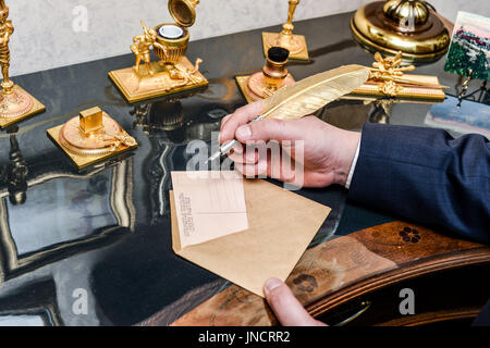 Penna in piuma con inkwell e documenti in bianco su sfondo di legno Foto Stock