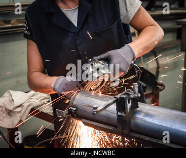 L'uso della smerigliatrice angolare in una lamiera di fabbrica. Foto Stock