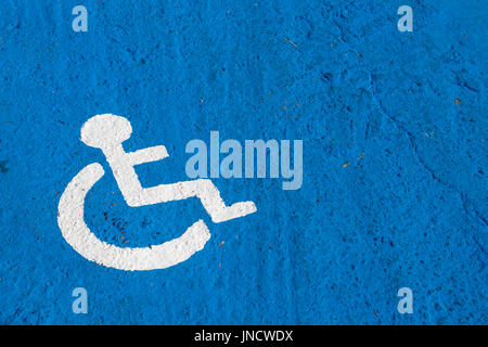 Bianco parcheggio disabili segno dipinto su sfondo blu Foto Stock