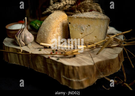 Grossi pezzi di formaggio con verdure su un pannello di legno Foto Stock
