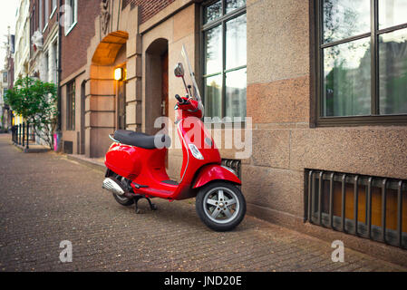 Uno scooter più popolari Trasporto in Amsterdam. Red vintage scooter parcheggiato su un marciapiede Foto Stock