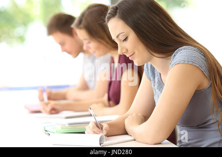 Vista laterale del concentrato di tre studenti di prendere appunti in classe Foto Stock