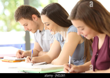 Tre studenti di prendere appunti durante una classe in una classe Foto Stock