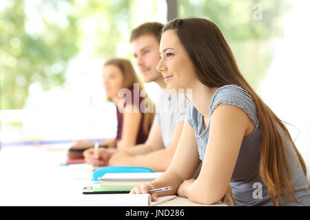 Gli studenti ascolto di una lezione in aula con altri compagni di classe in background Foto Stock