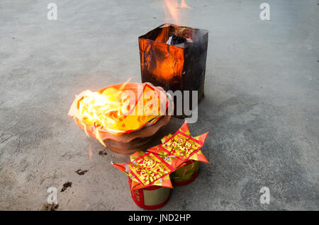 Persone bruciare joss carta oro e argento carta per il culto con la carta fatta a somigliare a denaro e bruciato come offerta sacrificale per pregare Dio e memo Foto Stock