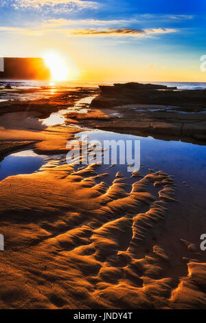 Bright warm Rising Sun su Royal National Park promontorio da Garie spiaggia mare piano della costa del Pacifico, Australia. Foto Stock