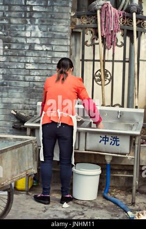 Donna cinese lavaggio piatti (cucina porter) nel piccolo ristorante all'aperto su Fengbao Rd, Fengtai District che è un suburban Pechino Foto Stock