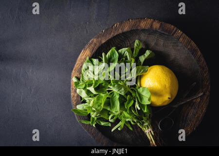 Di foglie di basilico fresco e succo di limone sulla piastra di legno su sfondo scuro. Vista da sopra con spazio copia, tonica immagine. Concetto di estate, la freschezza e il cibo fresco Foto Stock