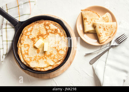 Crepes fatte in casa con burro in ghisa pan su sfondo bianco - fresco di cottura colazione casalinga Crepes Pancake cibo Foto Stock