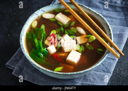 Giapponese zuppa di miso in vaso in ceramica nera sul tavolo di pietra, copia dello spazio. Asian zuppa di miso con tofu. Foto Stock