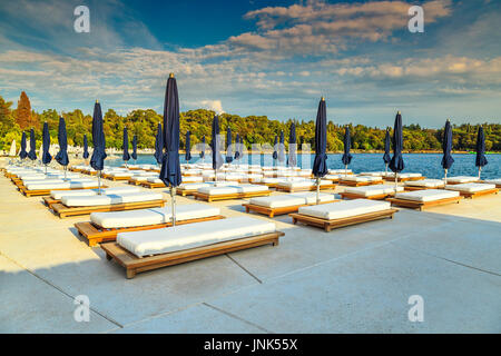 Sedie a sdraio e ombrelloni sulla spiaggia tropicale, Rovigno, Istria regione, Croazia, Europa Foto Stock