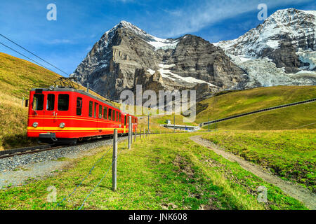 Famoso elettrico rosso retrò treno turistico che scendono dalla stazione Jungfraujoch(top d'Europa) in Kleine Scheidegg, Oberland bernese, Svizzera, e Foto Stock