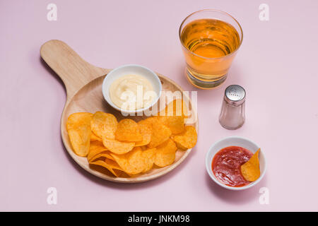 Il formaggio e la cipolla patatine con soft drink su sfondo rosa. Foto Stock