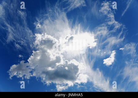 Sole splende attraverso le nuvole nel cielo blu Foto Stock