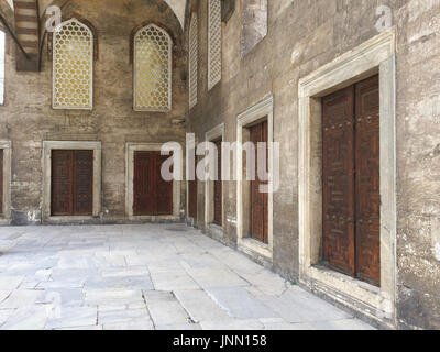 Portico con porte in una fila e griglie nel cortile di una antica moschea Foto Stock