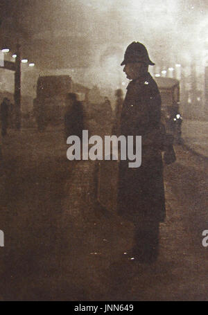 1934 - Un inglese 'Bobby' poliziotto in servizio durante un 'pea-souper" London fog. Foto Stock