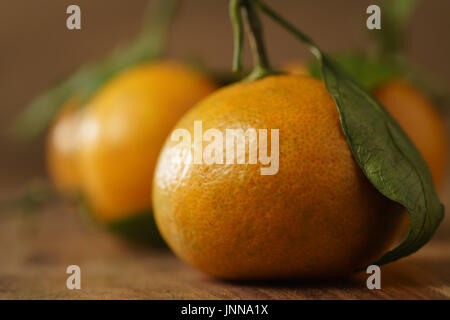 Tangerini organico con foglie sulla tavola di legno Foto Stock