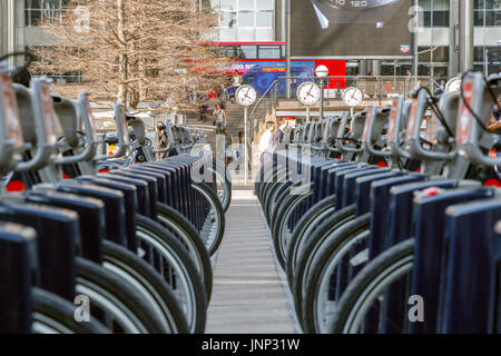 London, Regno Unito - 10 Maggio 2017 - Reuters Plaza a Canary Wharf visto attraverso due righe di Santander cicli a una docking station Foto Stock