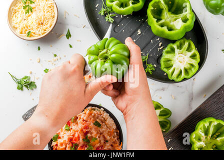 Ricette d'autunno. Home farcite peperone con carne macinata, carote, pomodori, erbe e formaggio. Il processo di cottura. Su marmo bianco tavola. Vista dall'alto. Woma Foto Stock