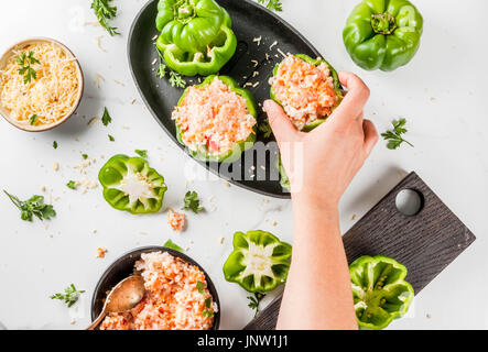 Ricette d'autunno. Home farcite peperone con carne macinata, carote, pomodori, erbe, formaggio. Il processo di cottura. Marmo bianco tavola. Vista dall'alto. Donna stea Foto Stock