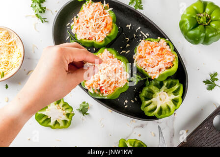 Ricette d'autunno. Home farcite peperone con carne macinata, carote, pomodori, erbe, formaggio. Il processo di cottura. Marmo bianco tavola. Vista dall'alto. Donna aggiungere Foto Stock