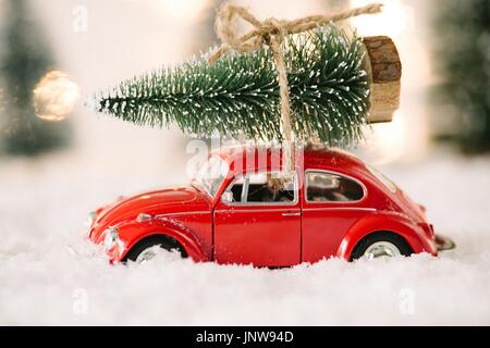 Little Red auto giocattolo che porta l'albero di Natale in coperta di neve la foresta in miniatura Foto Stock