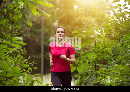 Giovane donna in esecuzione nella foresta boscosa Area - Formazione e di esercizio per il trail corsa maratona Endurance - Fitness su uno stile di vita sano concetto Foto Stock