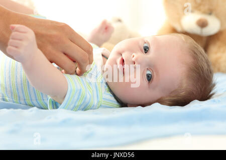 Ritratto di un happy baby guardando a voi e una madre mano toccandolo Foto Stock