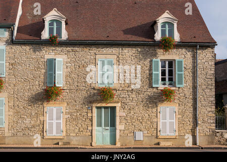 Beaune, Borgogna, Francia - 11 Ottobre 2015: casa in pietra con un pallido persiane verdi e rossi gerani in scatole di finestra, Beaune, Borgogna, Francia Foto Stock