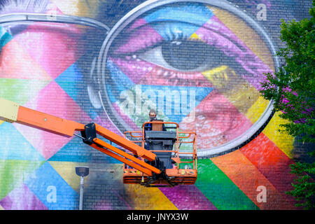 Bristol, Regno Unito. 31 Luglio, 2017. Artista Eduardo Kobra è raffigurato come egli applica i tocchi finali al suo formato gigante John Lennon murale sul lato della fabbrica di tabacco in Bedminster per Upfest 2017. Upfest che avviene nel corso di tre giorni è il più grande d'Europa libera, street art & graffiti festival e ora è nel suo nono anno. Credito: lynchpics/Alamy Live News Foto Stock