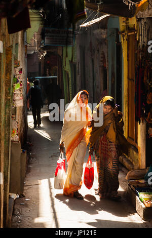 Due donne camminare lungo uno stretto vicolo di Varanasi Foto Stock