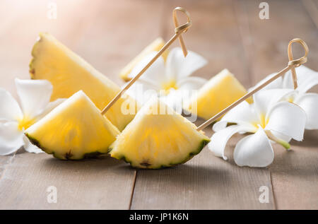 Ananas a fette su uno sfondo di legno popolari, frutta di stagione estiva Foto Stock