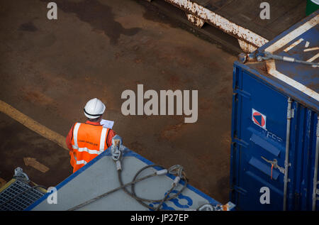 Materiali offshore coordinatore store (l'uomo) leggere il manifesto indossando tute rosso / tute. Credito: lee ramsden / alamy Foto Stock