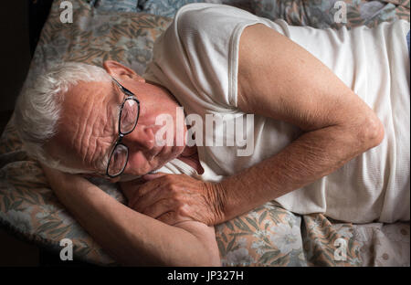 Senior uomo disteso nel letto con gli occhiali da lettura. Il riposo, insonnia e depressione concetto Foto Stock